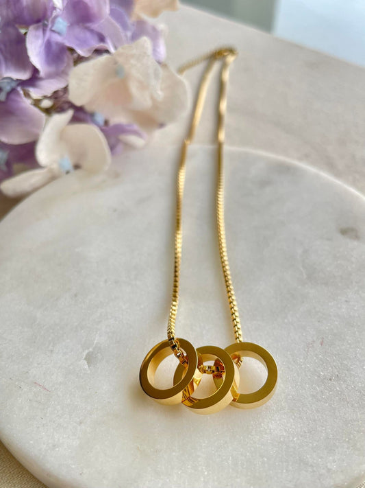 Three solid ring pendants on gold necklace