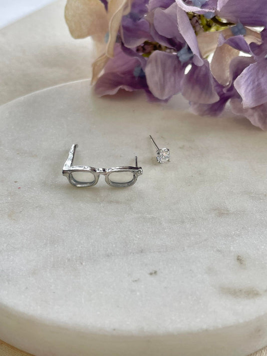 Silver glasses and single clear stud earrings
