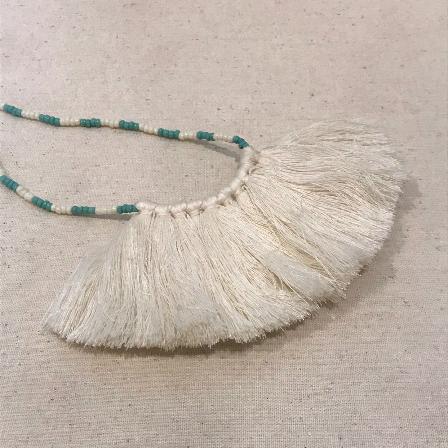 White tassel with green bead necklace